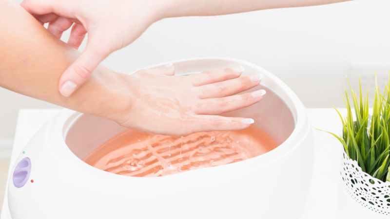 Aplikace parafínového vosku na ruce pro domácí hydrataci a péči o pokožku